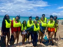 A group of people wearing life vests and standing on a beach