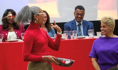 Carla Hall explains a recipe to April Woodard in front of expert panel.