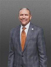 photo of Dr Glenn Carrington in a grey suit with an orange tie